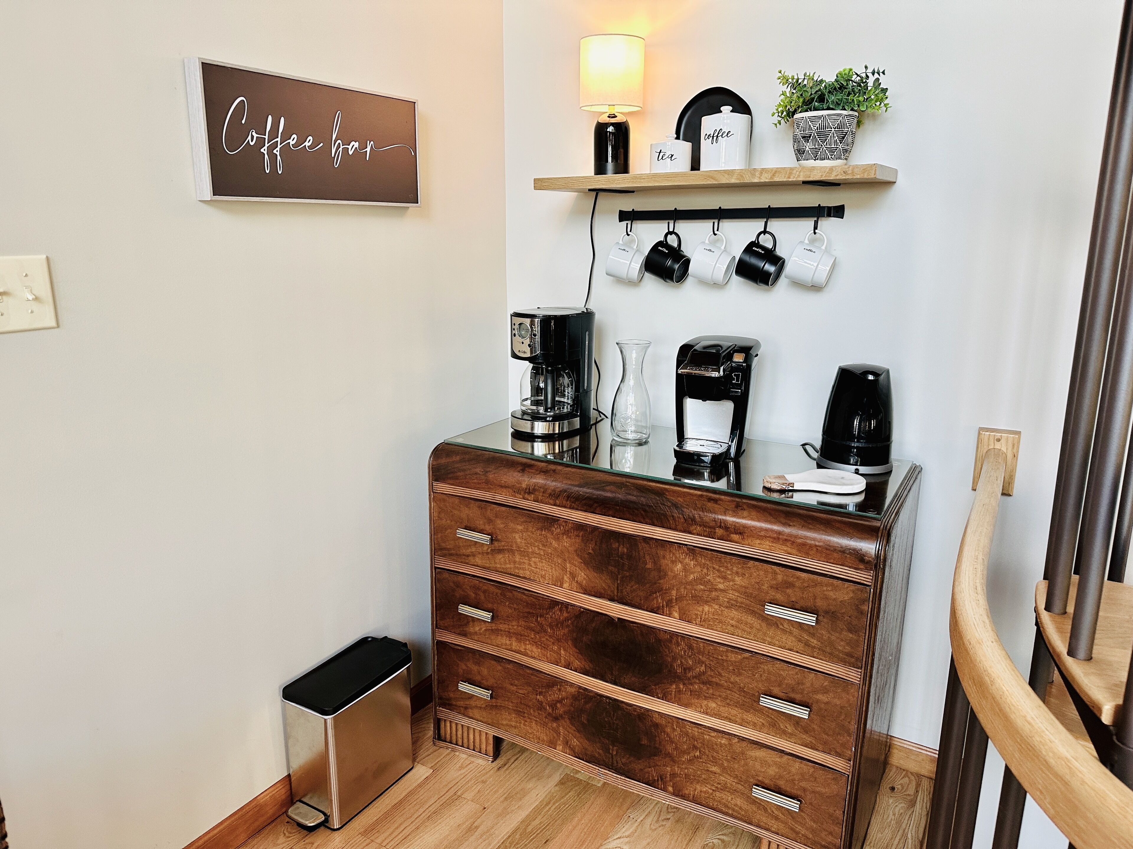 Un café avec une enseigne indiquant « Café », une étagère avec des tasses et une plante, et une machine à café.
