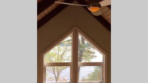 Ein Zimmer mit einer dreieckigen Decke und einem großen Fenster mit Blick auf Bäume und ein Gewässer.