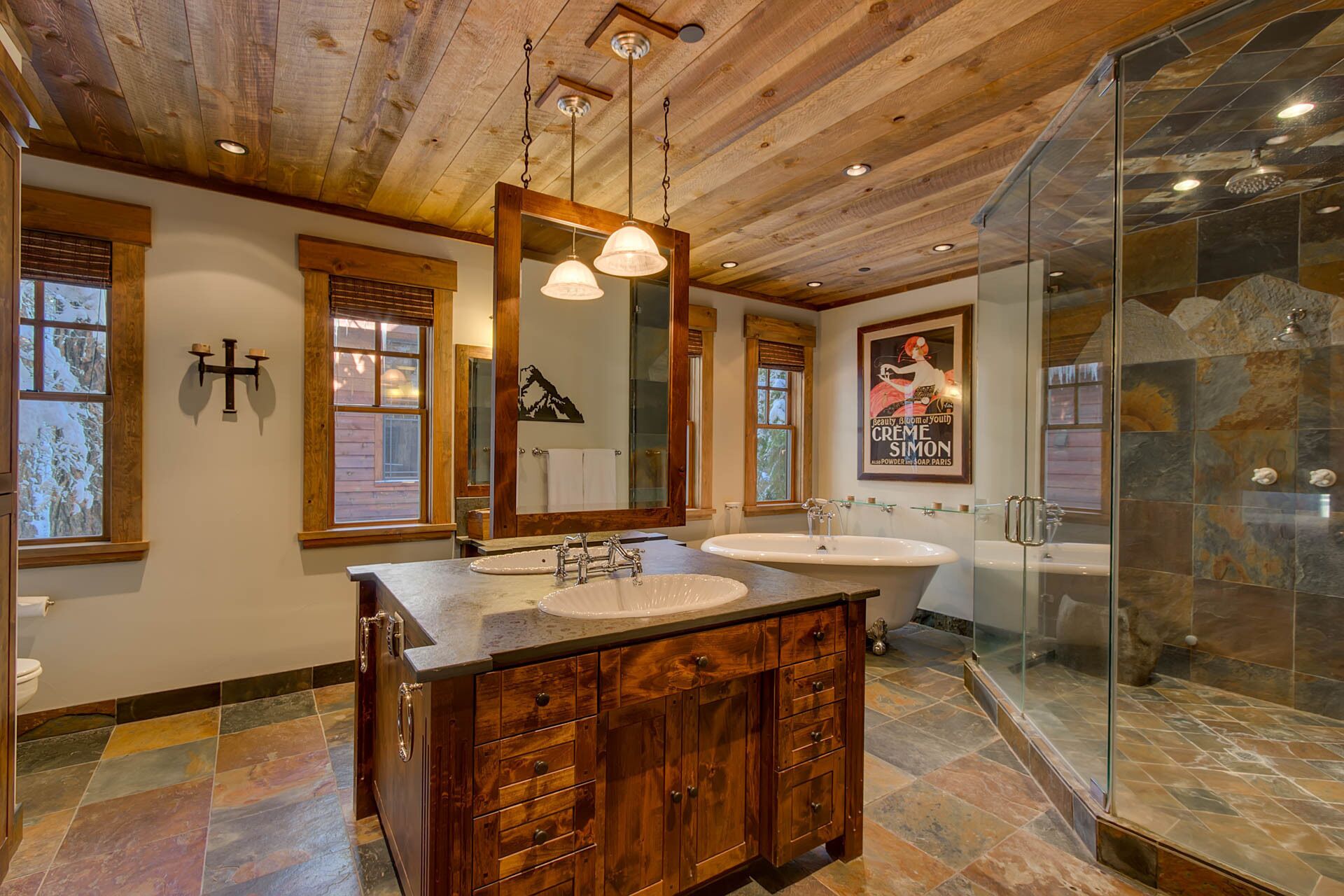 Une salle de bain avec des poutres en bois au plafond, un grand miroir, deux lavabos et une douche à parois de verre.
