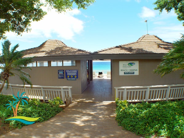 A pathway leading to beach cabanas with a view of the ocean.
