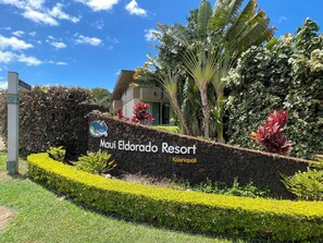 A sign for Maui Eldorado Resort with a stone wall and tropical landscaping.