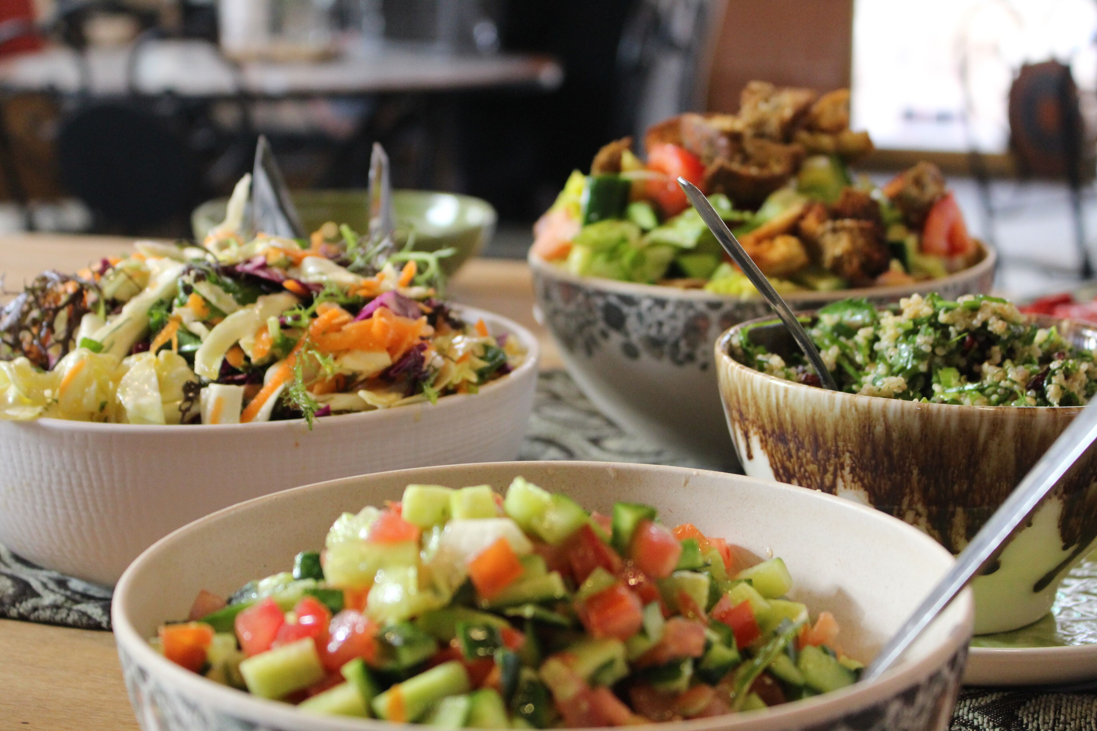 Uma mesa com tigelas de salada e outros pratos.