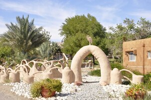 Un jardín con elementos escultóricos, incluyendo un arco grande y una escultura de pájaro.