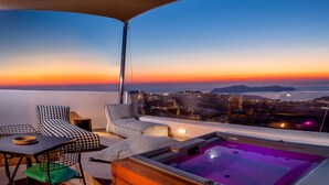 A rooftop terrace with a view of the city at sunset, a hot tub, and modern seating. - Santorini Soul Villas (Santorini)