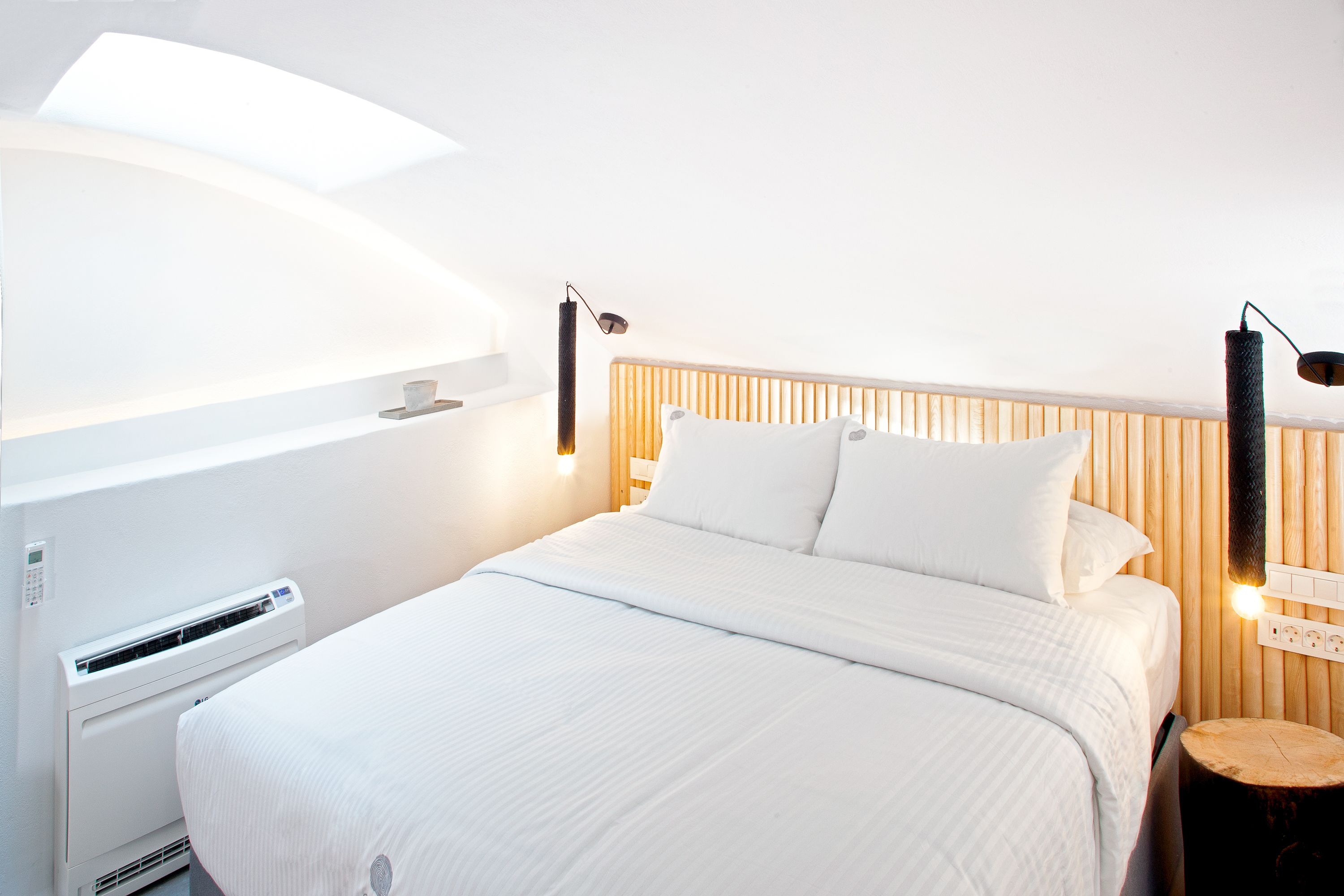 Een moderne hotelkamer met een groot bed, een nachtkastje, een wandradiator en een houten hoofdeinde.