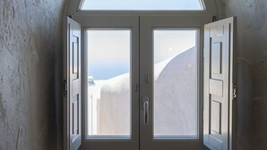 A room with a large arched window, a door, and a wall-mounted telephone. - Santorini Soul Villas (Santorini)