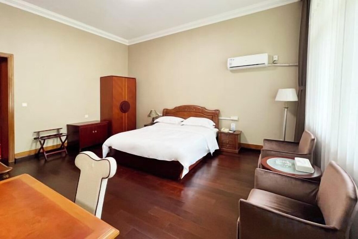 A hotel room with a bed, bedside table, lamp, and a chair.
