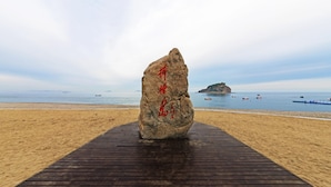 A large rock with inscriptions on a wooden platform at a beach. - Dalian Bangchui Island Hotel (Dalian)