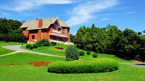 A large, red brick house with a white porch and a well-maintained lawn. - Dalian Bangchui Island Hotel (Dalian)