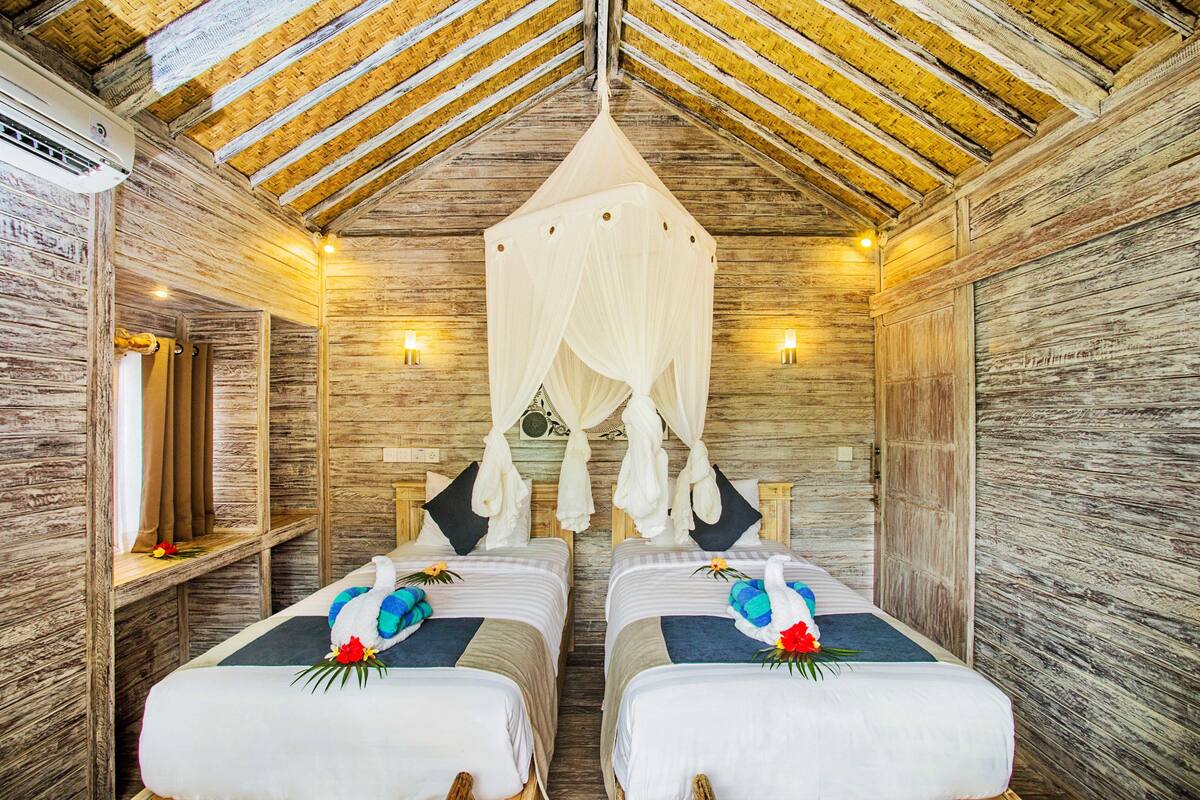 Une chambre avec deux lits, des murs en bois, un plafond en pente et un lit à baldaquin.