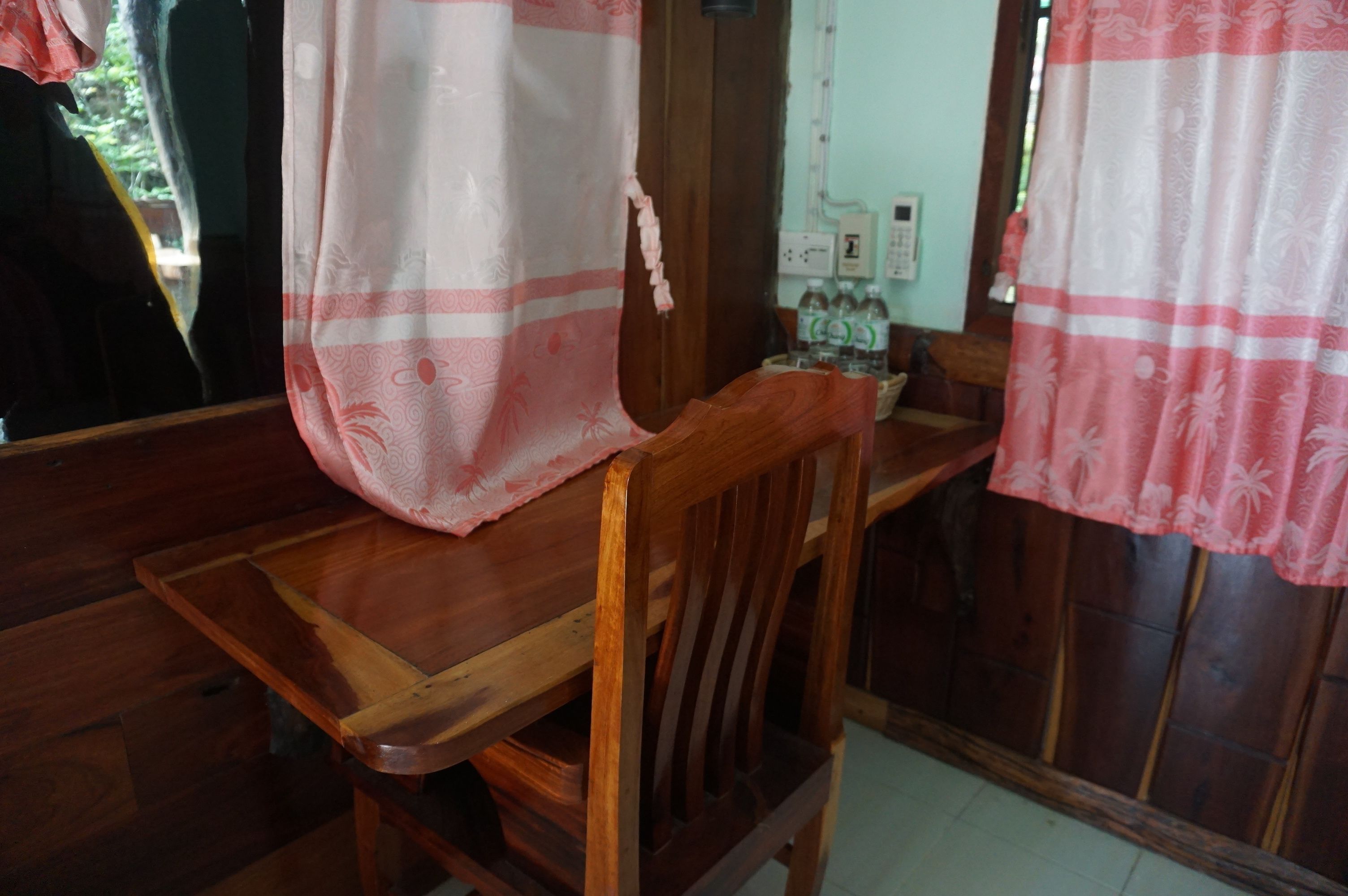 A wooden chair with a floral-patterned curtain partially covering it.
