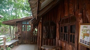 A rustic wooden building with a bench and a stone table outside. - Rai Aeifoon Resort (Thep Sathit)