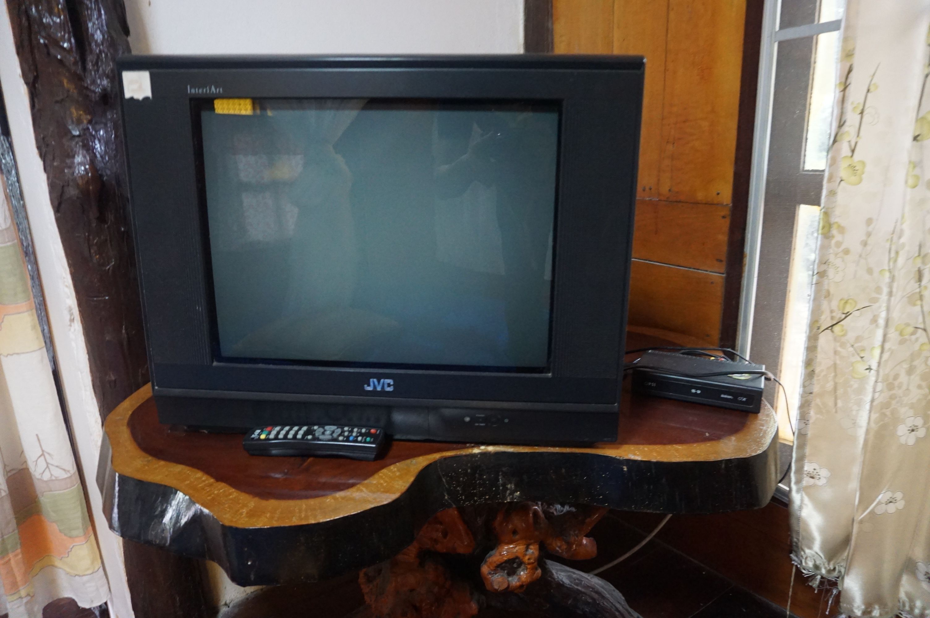 Et JVC fjernsyn på en træfod med fjernbetjening og DVD-afspiller.
