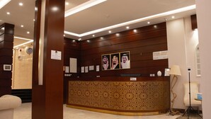 A reception area with a wooden reception desk, a clock, and framed pictures on the wall.