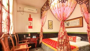 Ein traditionell eingerichteter Raum mit einem Himmelbett, einem Schreibtisch mit Stuhl und einem Fernseher.