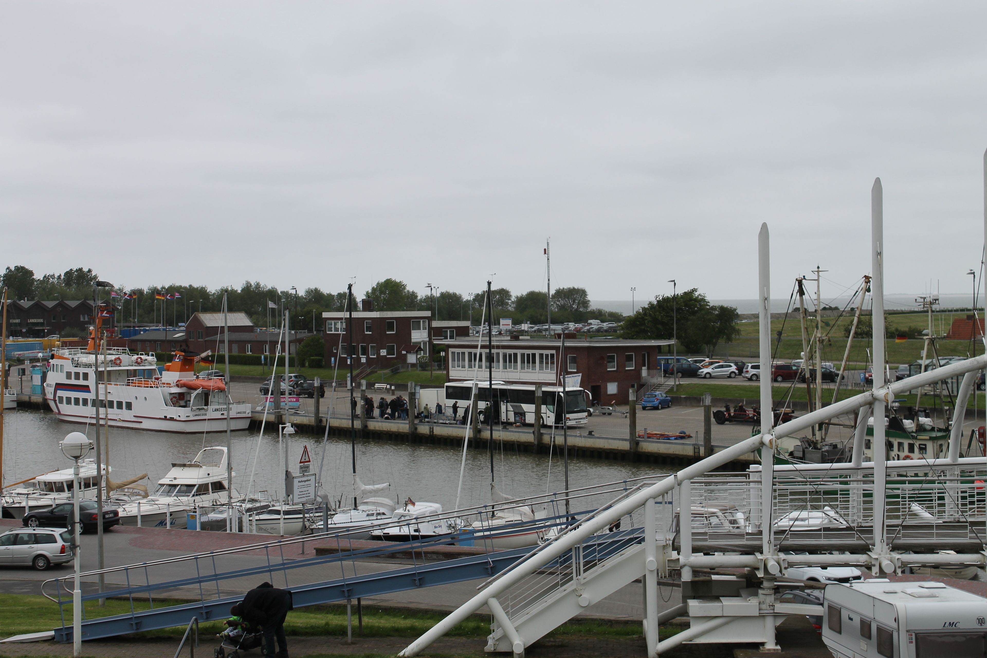 Un puerto deportivo con barcos amarrados, un puente peatonal y edificios al fondo.