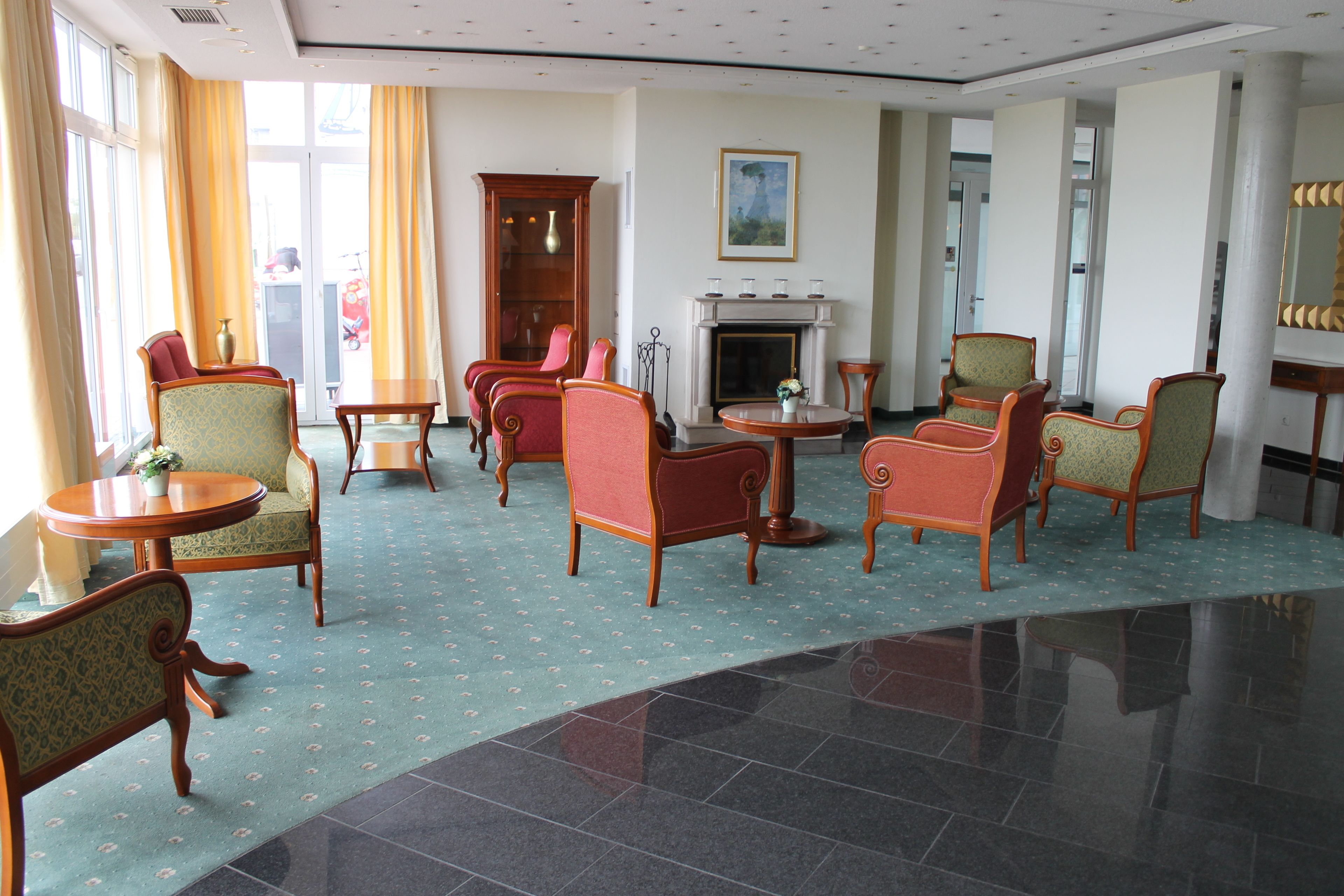 A hotel lobby with multiple seating areas, a fireplace, and large windows with curtains.