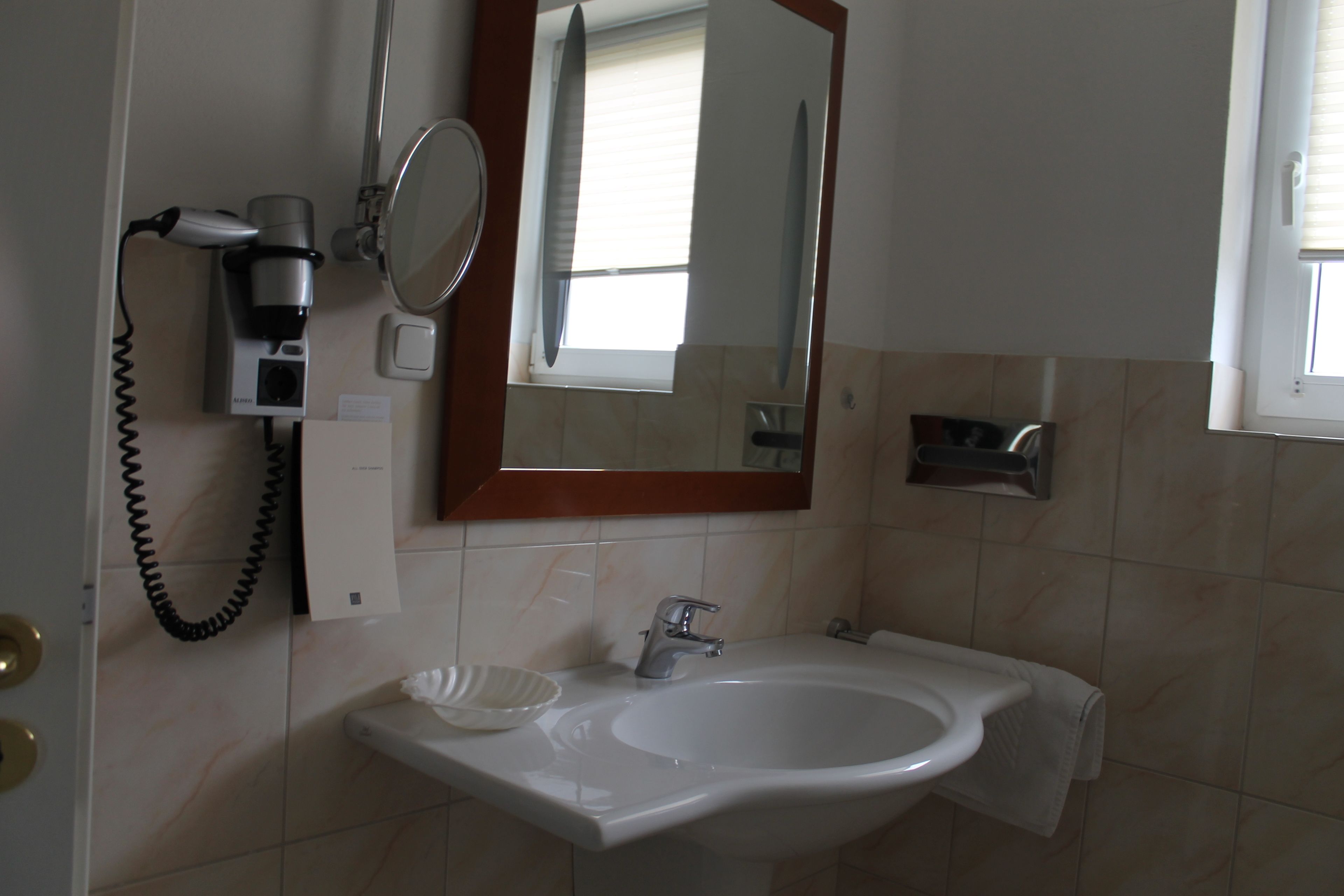 A bathroom with a sink, mirror, and hairdryer.