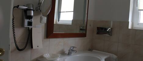 A bathroom with a sink, mirror, and hairdryer.