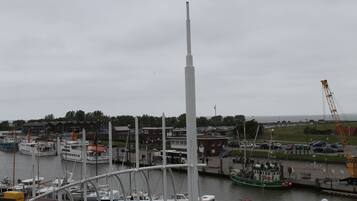 A marina with boats docked, a tall white structure, and a crane in the background.