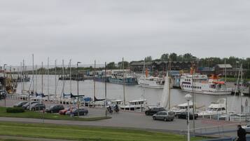 A marina with boats docked, a pedestrian walkway, and a building in the background.