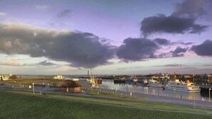 Un port de plaisance avec plusieurs bateaux amarrés, un petit bâtiment et une zone herbeuse au premier plan.