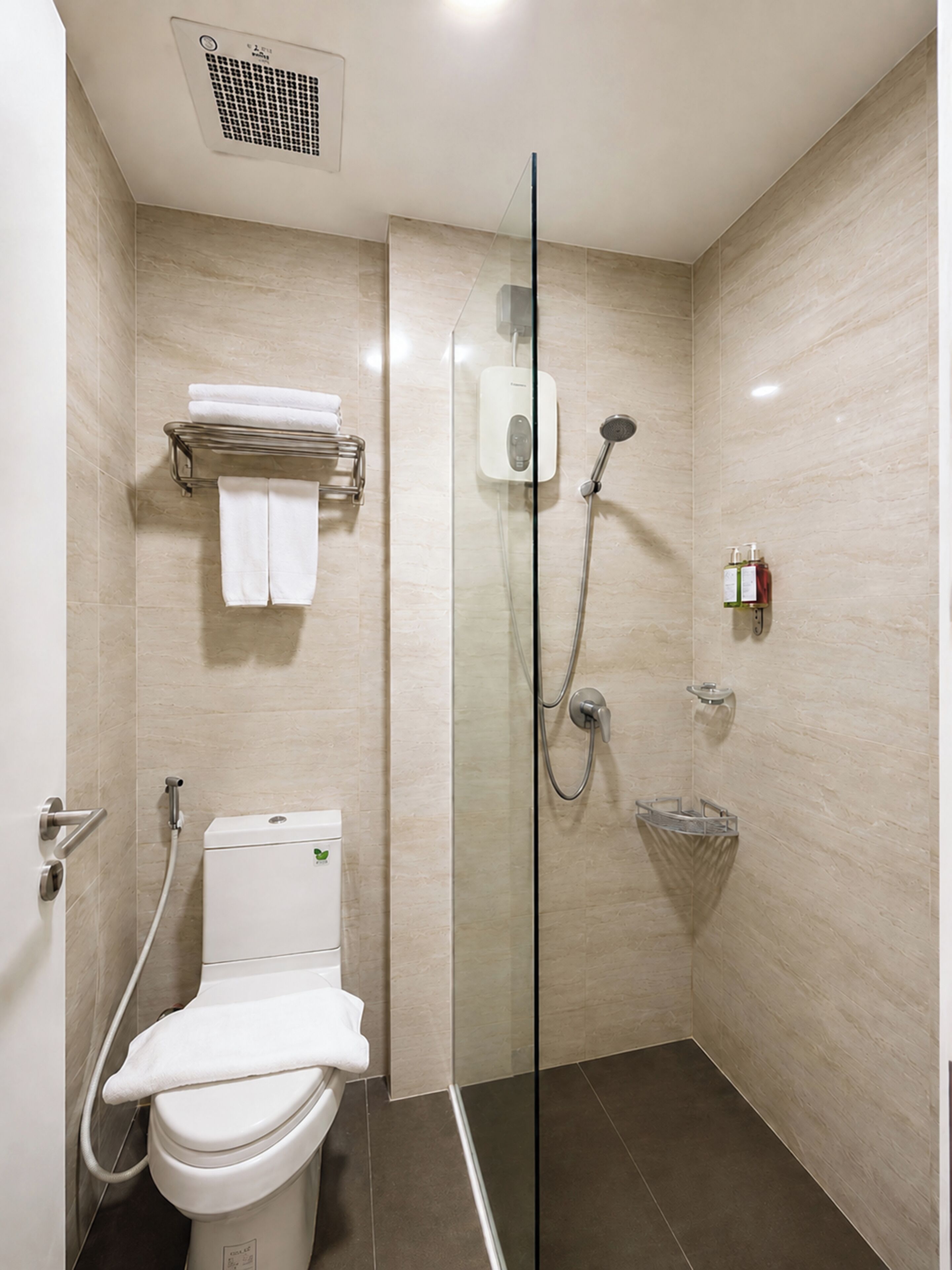 Une salle de bain moderne avec une douche à parois de verre, des toilettes, un porte-serviettes et un distributeur de savon.