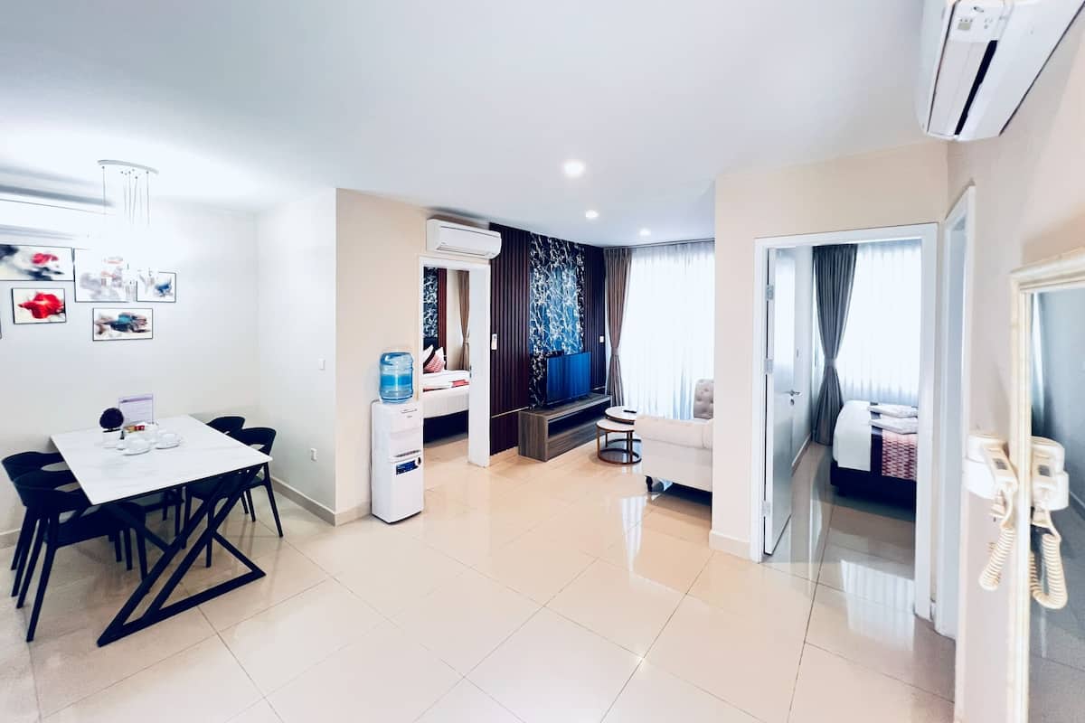 A modern hotel room with a dining area, a water dispenser, a sofa, and a telephone.