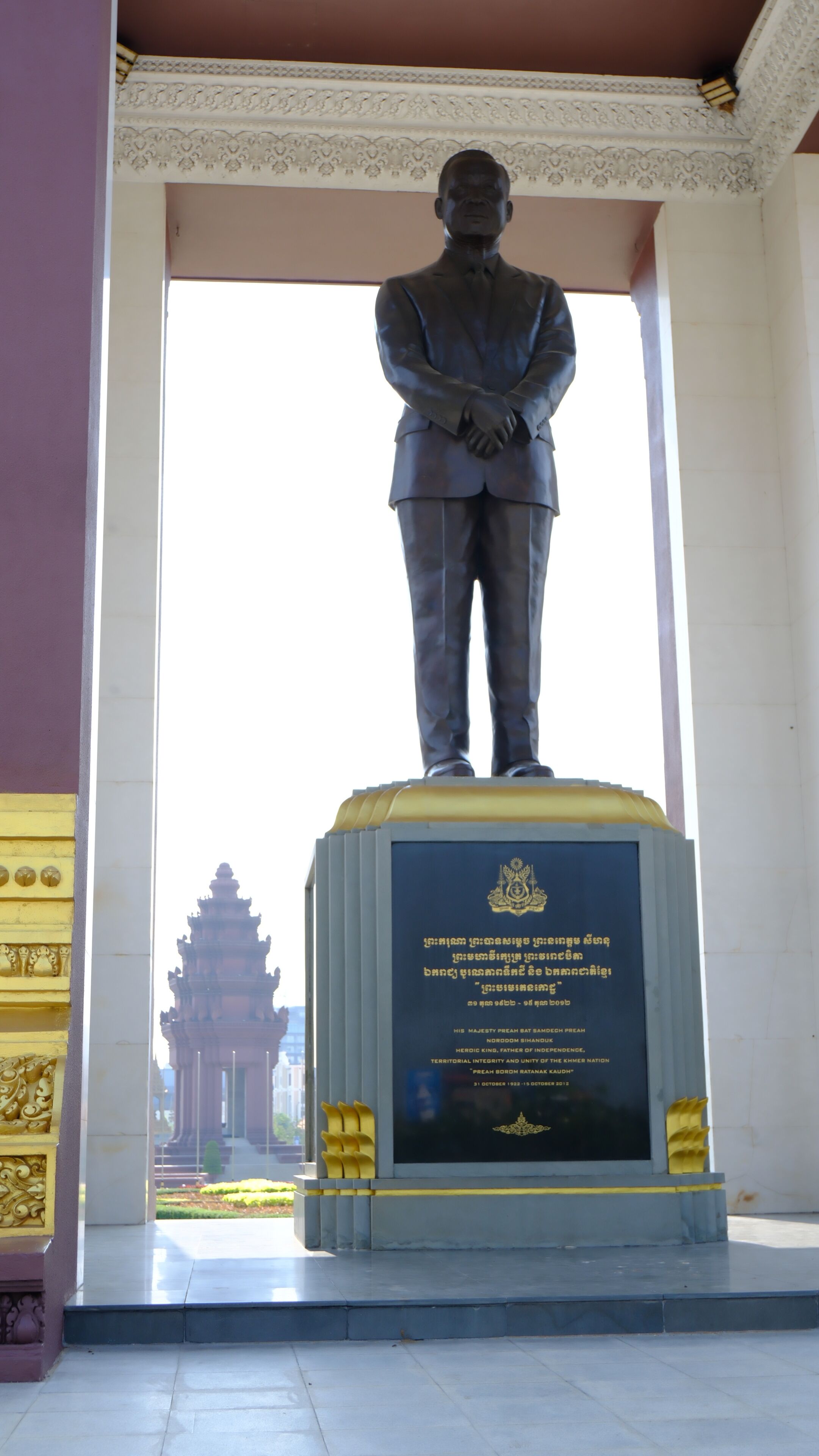 Una estatua de un hombre con traje sobre un pedestal con una placa.