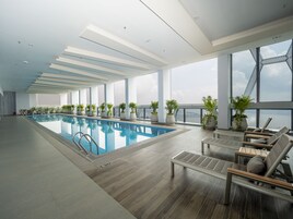 A modern indoor swimming pool with a clear view of the city skyline through large windows.