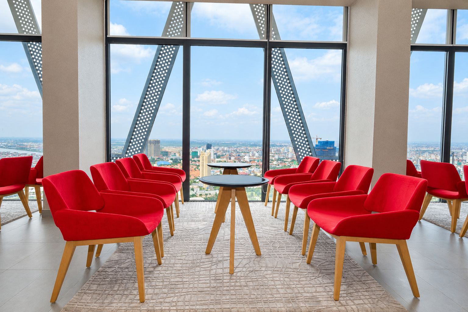 A conference room with red chairs arranged around a central table, large windows offering a cityscape view.