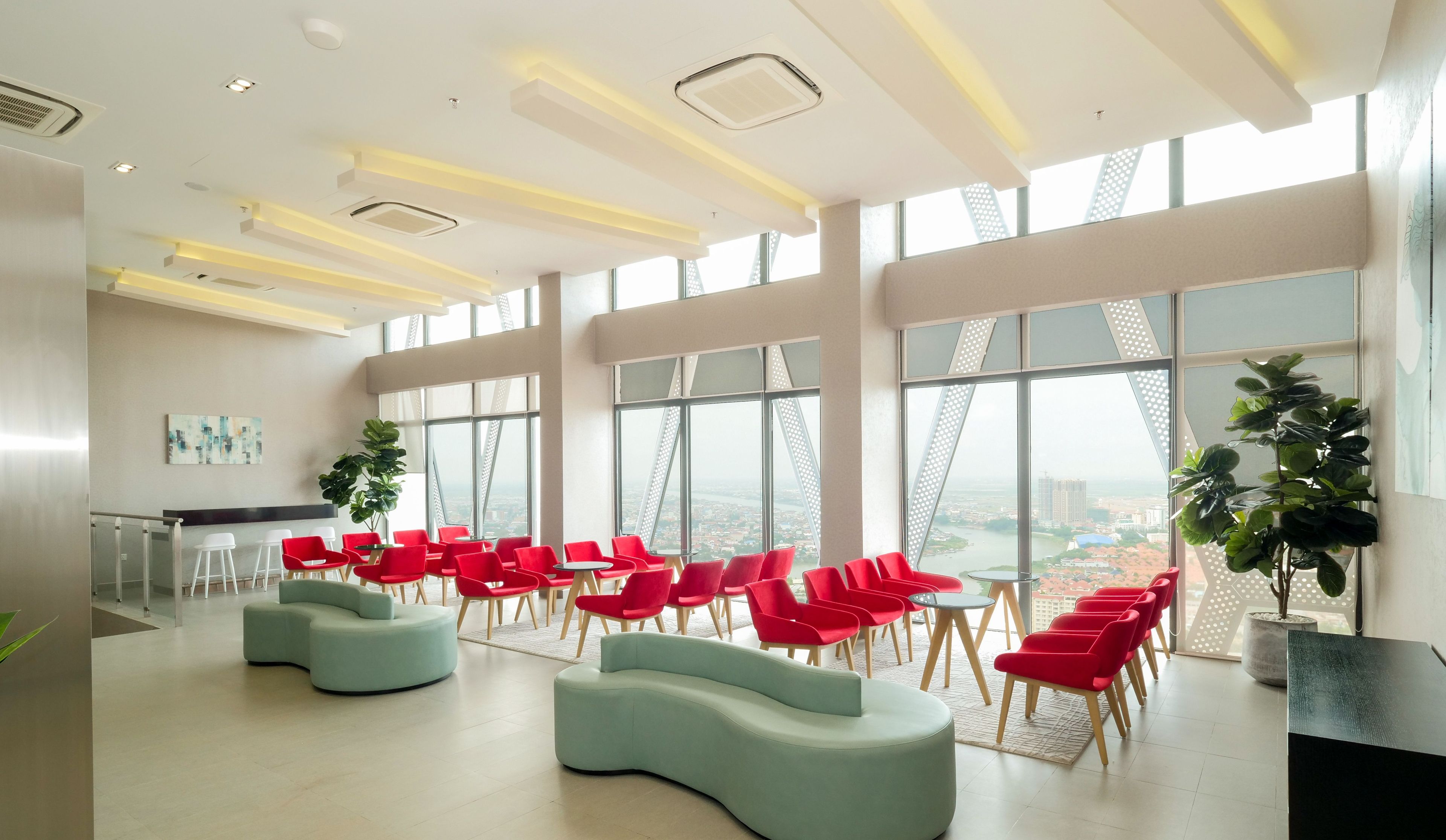 A spacious room with large windows, red chairs, and a light blue sofa.
