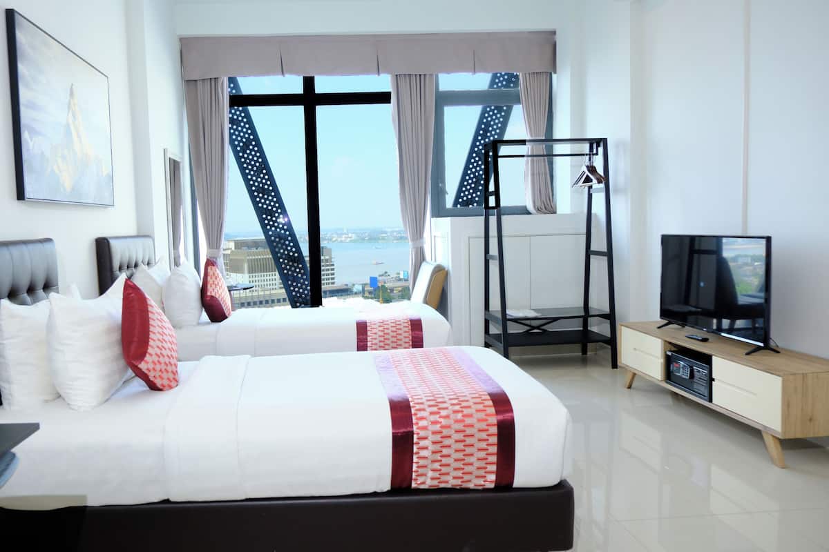 A hotel room with a bed, a TV, a desk, and a view of the city.