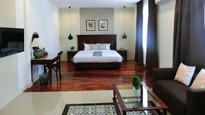 A hotel room with a large bed, a sofa, a TV, a desk, and a chandelier. - Bloom Boutique Hotel and Cafe (Vientiane)