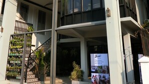 A modern hotel with a large entrance, a balcony with plants, and a signboard advertising the hotel. - Bloom Boutique Hotel and Cafe (Vientiane)