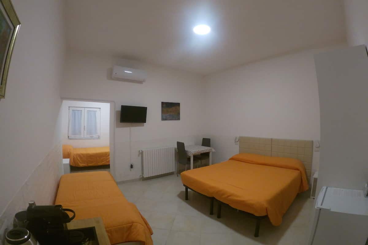 A small, clean room with two beds, a desk, a chair, and a radiator.
