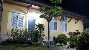 A yellow building with white shutters, a tree in the front yard, and a stone pathway. - Ostello Villafranca (Pignola)