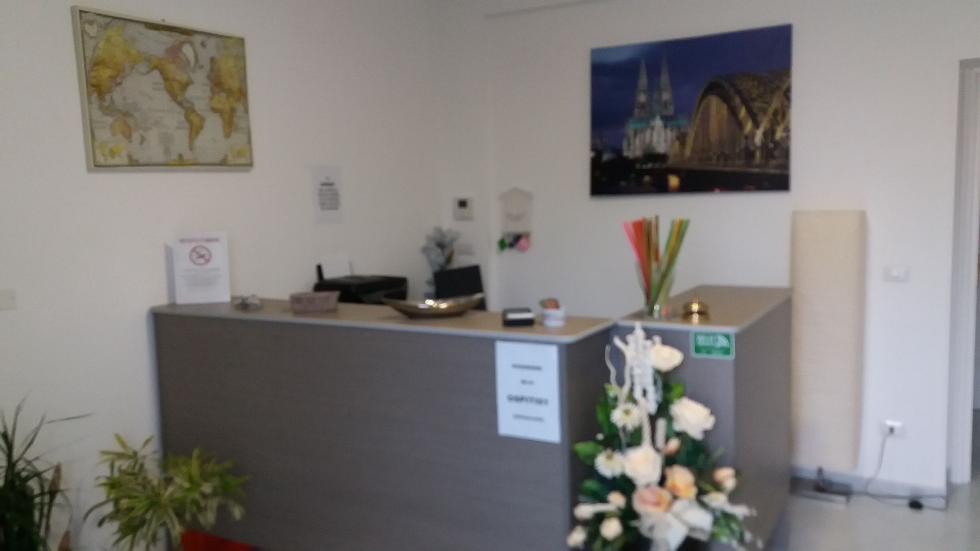 Un comptoir d’accueil avec un ordinateur, une plante et un panneau indiquant l’emplacement de la zone fumeurs.
