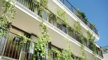 A multi-story building with balconies covered in greenery.