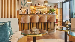Een moderne hotel lobby met een bar, zithoekjes en een groot raam dat voor natuurlijk licht zorgt.