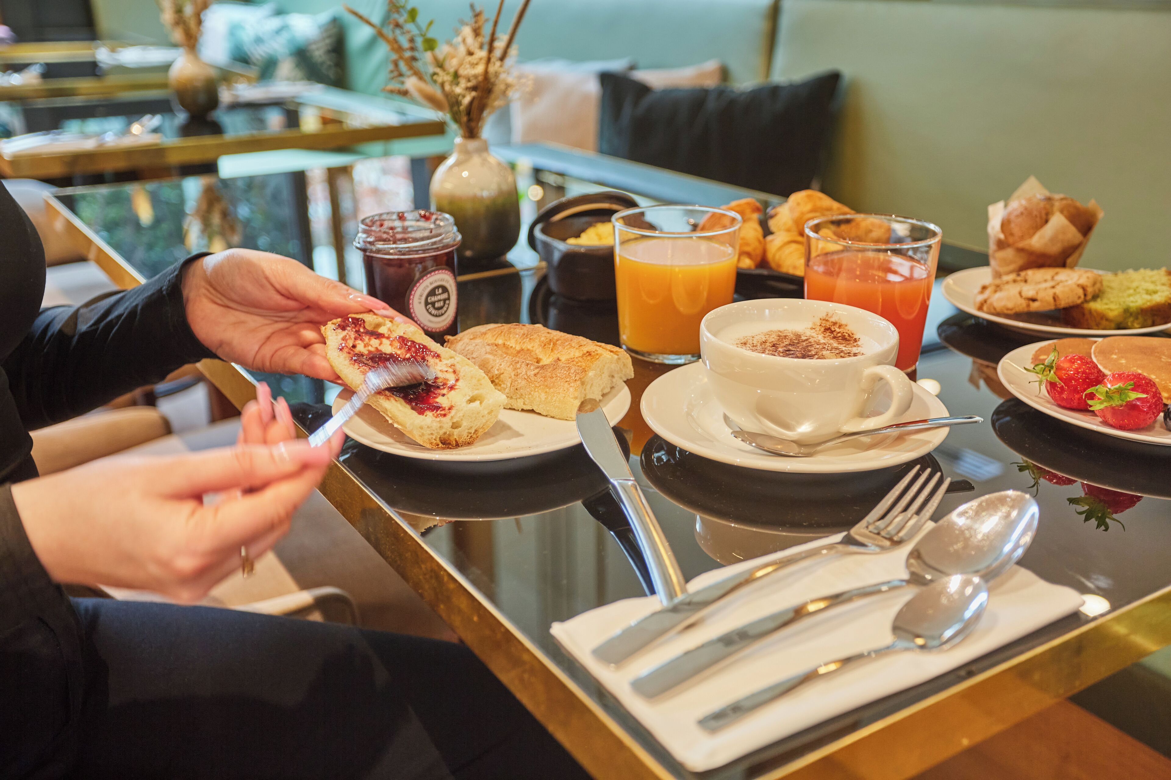 A breakfast setting with croissants, pastries, a cup of coffee, and a glass of orange juice on a table.