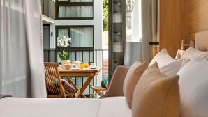 Hotelkamer met een bed, een eettafel met ontbijtartikelen, een stoel en uitzicht op het balkon.