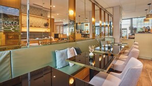 Een modern restaurant met een lange toonbank, zachte zitplaatsen en een groot raam met uitzicht op de stad.