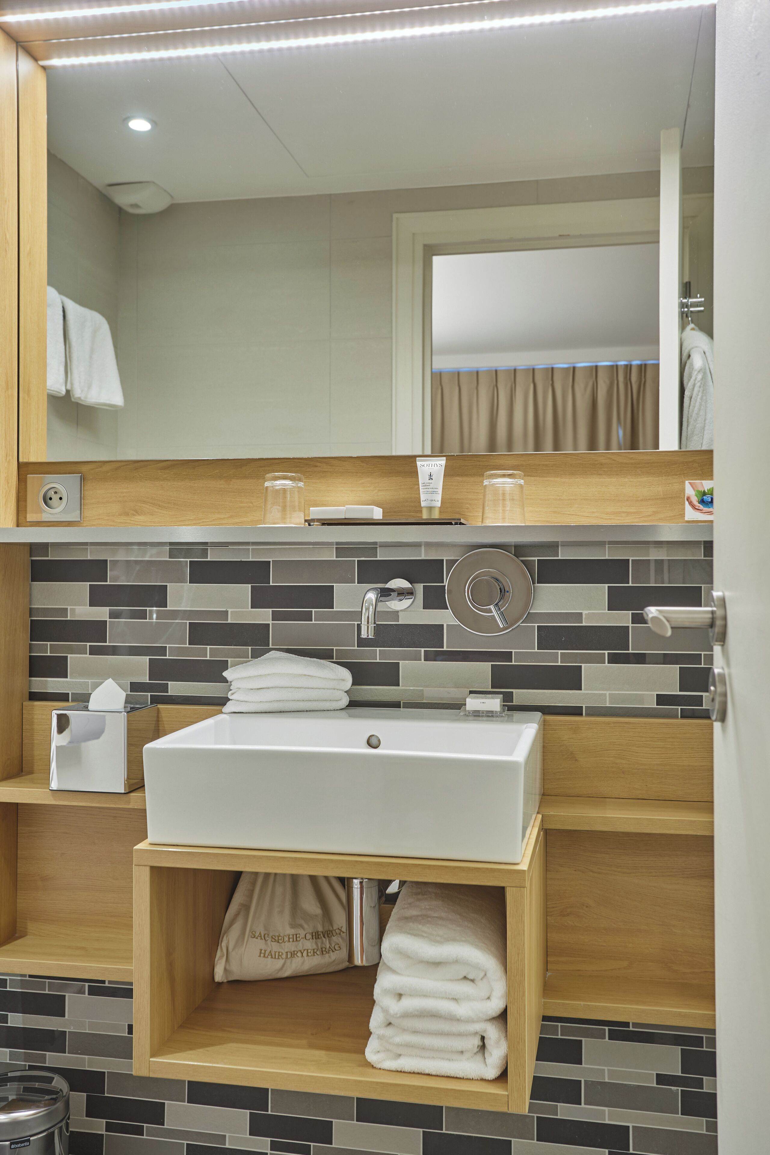 A modern bathroom with a white sink, a mirror, and a towel rack.