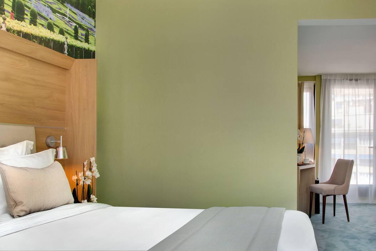 Ein Hotelzimmer mit einem Bett, einem Schreibtisch, einem Sessel und einem Bild an der Wand.