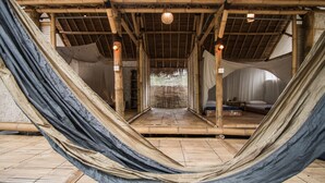 A hammock in a room with bamboo flooring and a thatched roof. - maoMeno (Gili Meno)