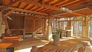 A spacious wooden interior with a high ceiling, large windows, and a central wooden table. - maoMeno (Gili Meno)