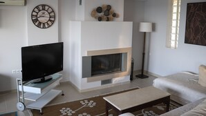 Una sala de estar moderna con una televisión de pantalla plana sobre un mueble, una chimenea, un sofá y una mesa de centro.