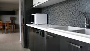 Una cocina moderna con encimera blanca, microondas, fregadero y salpicadero de azulejos.