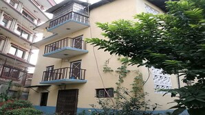 A multi-story building with balconies and a garden area. - The Nepali Hive (Kathmandu)